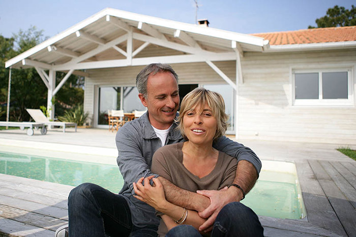 Mature couple smiling by their pool