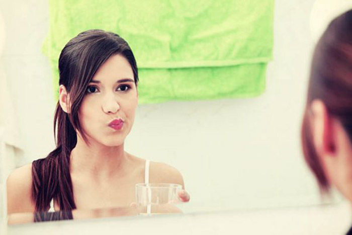 Woman swishing water in her mouth