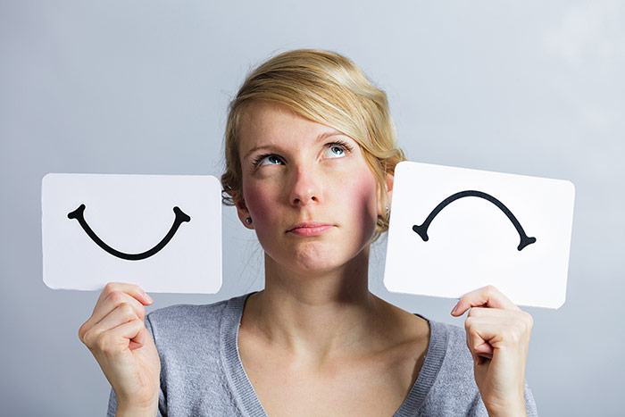 Woman holding smile and frown symbols